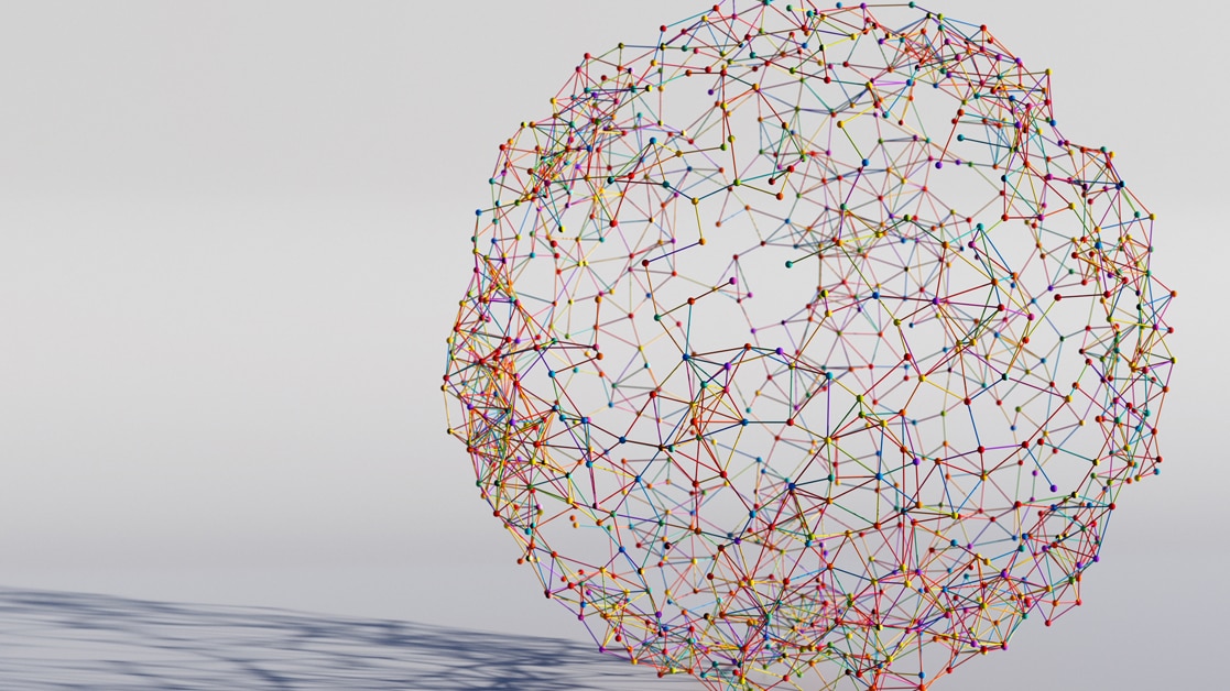 Multi-colored globe made from connected sticks, resting on a white background